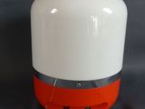 une enceinte blanche et orange posée sur une surface noire