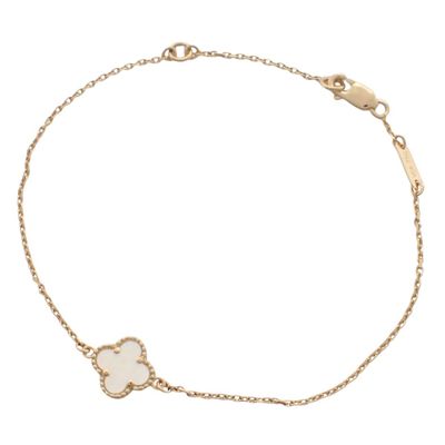 un bracelet en or avec une breloque en forme de trèfle blanc suspendue à une chaîne