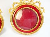 pair of red and gold picture frames with a red velvet cover