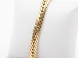 a close up of a gold bracelet on a white pillow