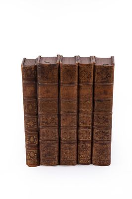 several old books stacked on top of each other on a white surface