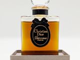 un gros plan d'un flacon de parfum posé sur un plateau en bois