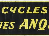 un panneau noir et jaune sur lequel on peut lire « Cycles Jacques Anquetti »
