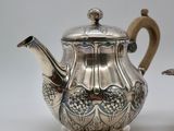 two silver teapots sitting next to each other on a table