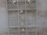 a white metal shelf with a bird cage on top of it