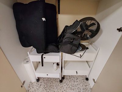 une valise et un ventilateur dans un coin d'un placard