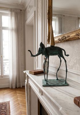 a statue of an elephant on a mantle in a room