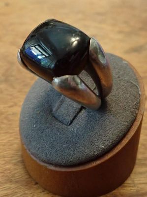 a ring with a black stone on it sitting on a stand