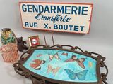 a sign that says gendarmerie and a vase with butterflies on it