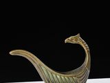a gold and green vase with a bird on top of it