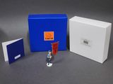 une petite figurine qui se trouve à côté d'une boîte bleue