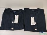 une paire de pulls pour homme, encore étiquetés, posés sur une table