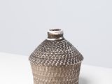une photo d'un vase marron et blanc posé sur une table blanche