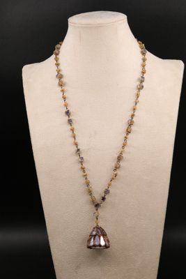 un collier auquel est suspendue une clochette en verre, sur un mannequin