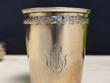a silver cup with a monogram on it sitting on a table
