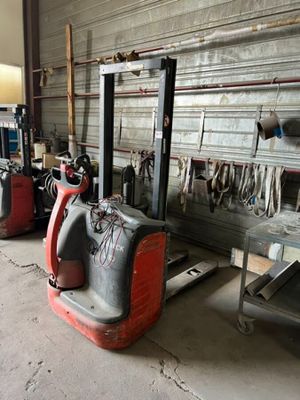 a red fork lift in a garage with other tools