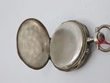 a silver pocket watch with a red string around it
