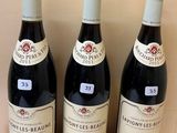 three bottles of wine sitting on a wooden shelf in front of a wall