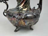 a silver tea pot on a stand on a table
