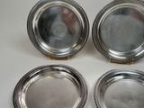 four silver plated dishes on a white surface with gold handles
