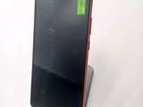 the back of a black and red cell phone sitting on top of a white table