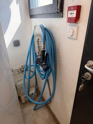 un tuyau bleu fixé au mur, à côté d'une porte noire