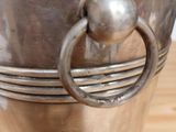 a silver bucket with a ring handle on a wooden table