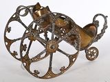 une calèche ancienne en laiton, avec ses roues, sur fond blanc