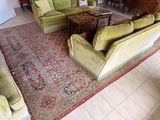 une photo d'un salon avec des canapés verts et un tapis