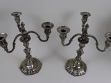 two silver candelabs on a white table with a white background