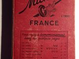 un vieux livre rouge posé sur une table à côté d'une table blanche