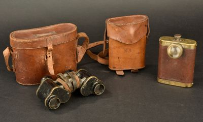 two old leather bags and a pair of binoculars on a black background