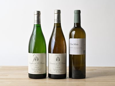 trois bouteilles de vin posées les unes à côté des autres sur une table en bois
