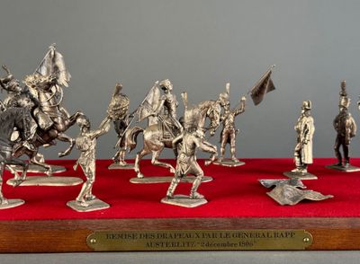 silver figurines of knights on horses and riders on a red surface