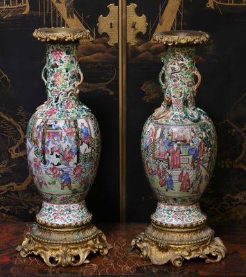 une paire de vases orientaux posés sur un socle devant un papier peint oriental
