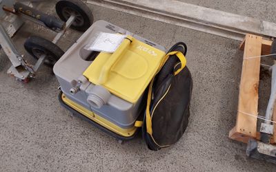 une valise jaune et noire posée par terre à côté d'un chariot