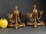 two golden vases sitting next to an apple on a table