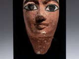 a close up of a clay mask with a black background