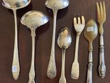 a lot of silver spoons and forks laid out on a table