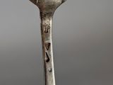 a silver spoon with a bird on it sitting on a table