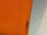 a close up of an orange leather wallet on a white surface