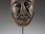 a wooden mask on a stand with a gray background