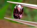 quelqu'un tient une paire de pinces ornée d'un diamant violet