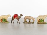 three figurines of animals and a camel in a row on a floor