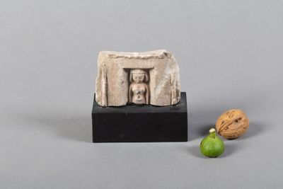 une figurine représentant une femme dans une vitrine et une noix posée sur un socle