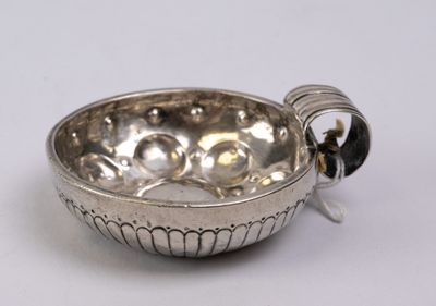 a silver bowl with a handle on a white surface