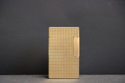 un briquet doré posé sur une table près d'un mur noir