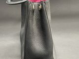 black leather handbag with pink interior on grey background