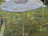 a table and chairs in the grass with a bench in the background