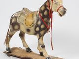 statue d'un cheval sellé posée sur une planche en bois